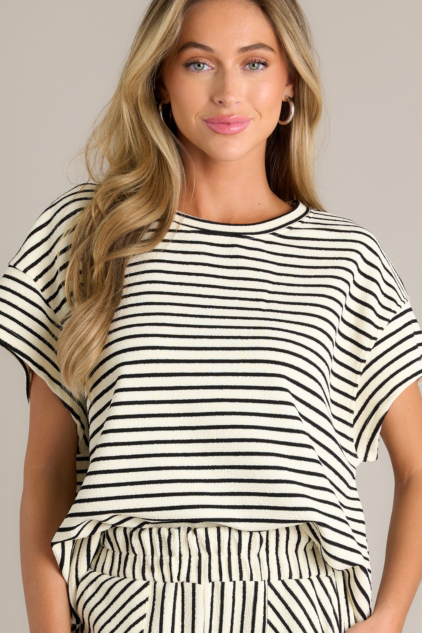 This black stripe top features a crew neckline, a thick textured material, a thick hemline, and short sleeves.