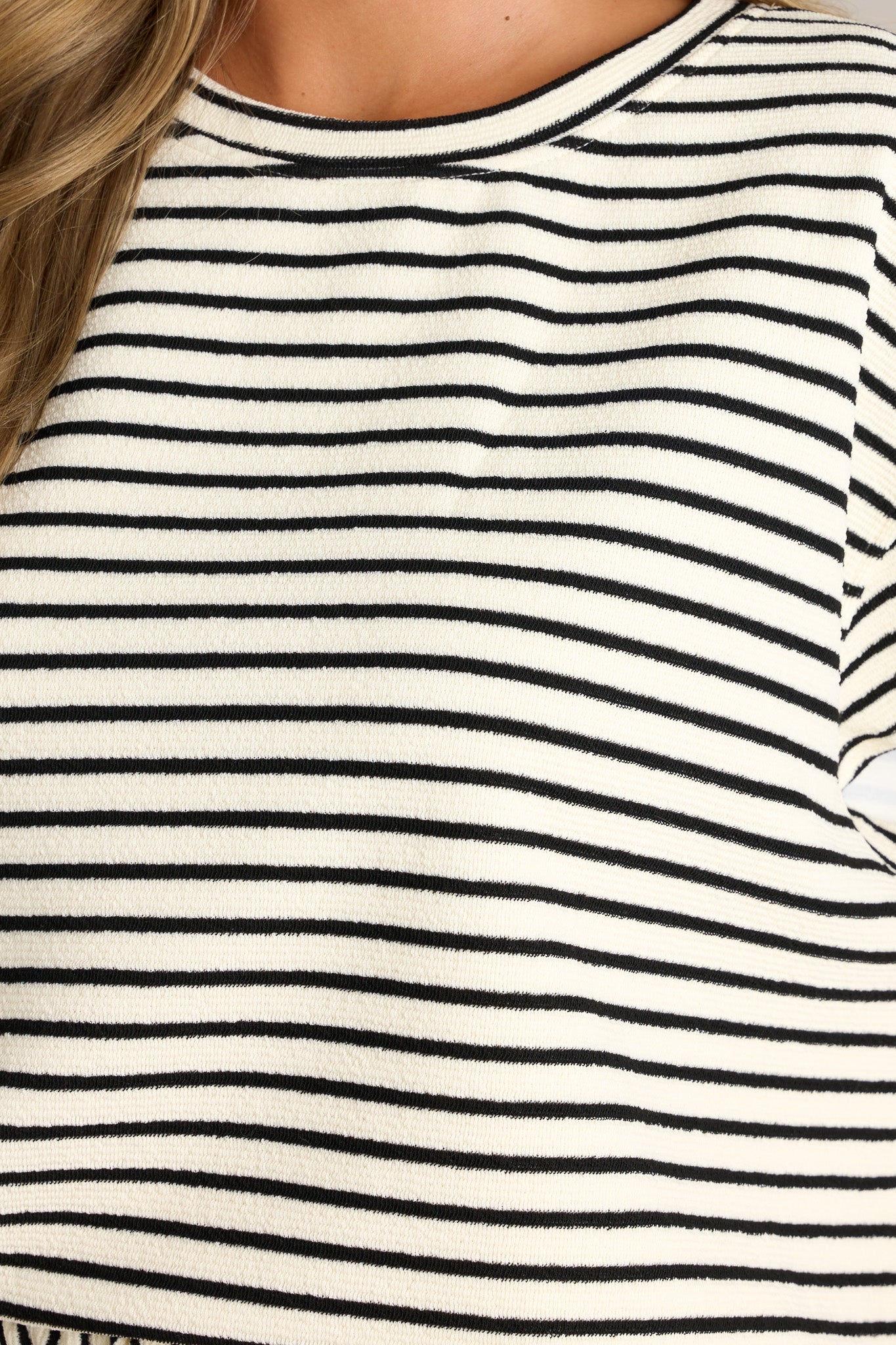 Close-up of the black stripe top showing the crew neckline, thick textured material, and thick hemline.