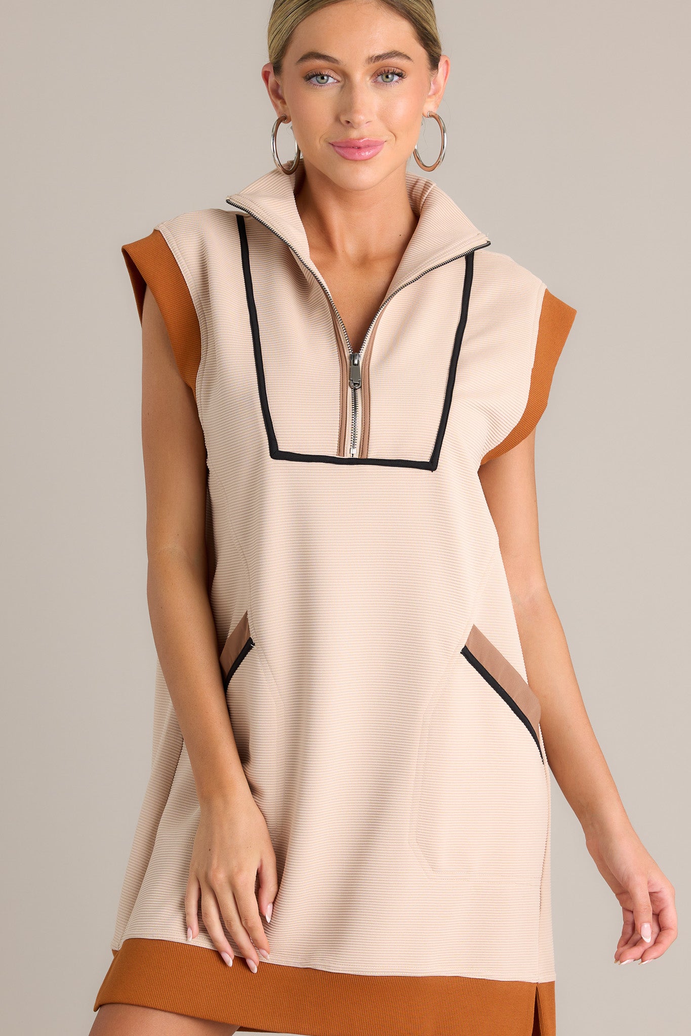 Front view of this taupe mini dress featuring a collared v-neckline, a functional zipper front, ribbed detailing, functional front pockets, a split hemline, a short cap sleeves.