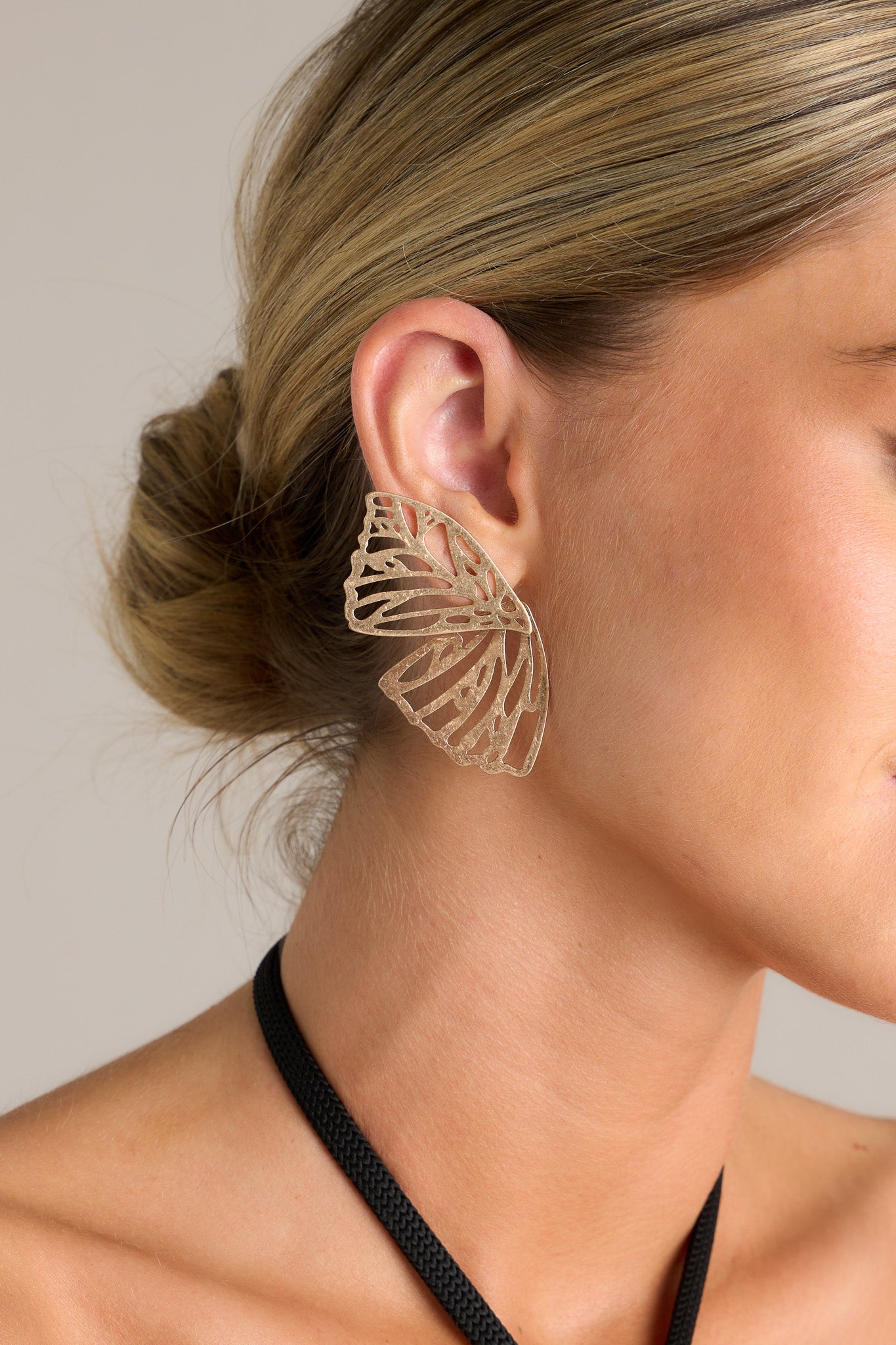 These gold earrings feature a butterfly wing, a worn gold finish, and secure post backings.