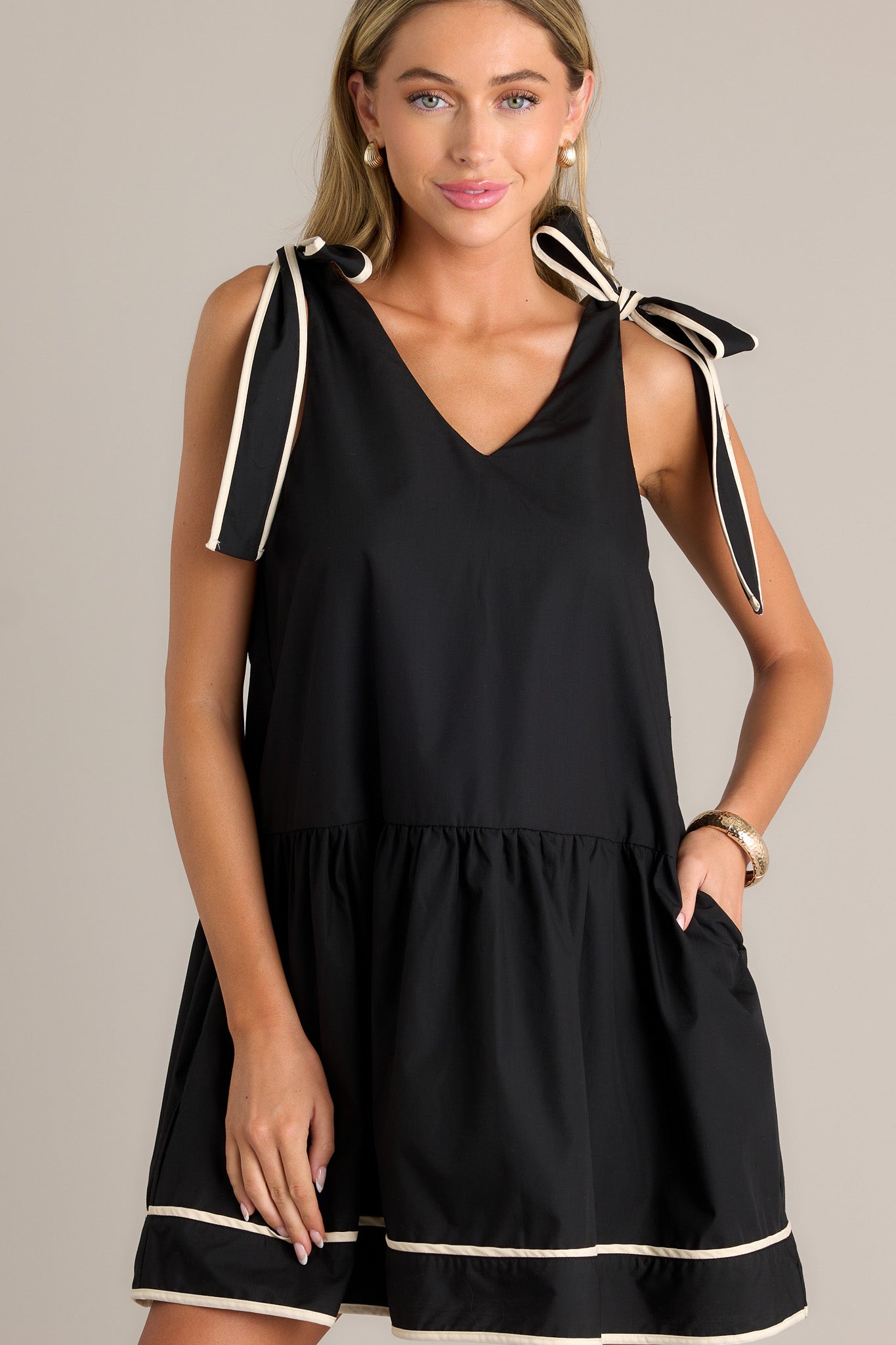 Focused view of the black mini dress highlighting the functional hip pockets and high contrast trim.