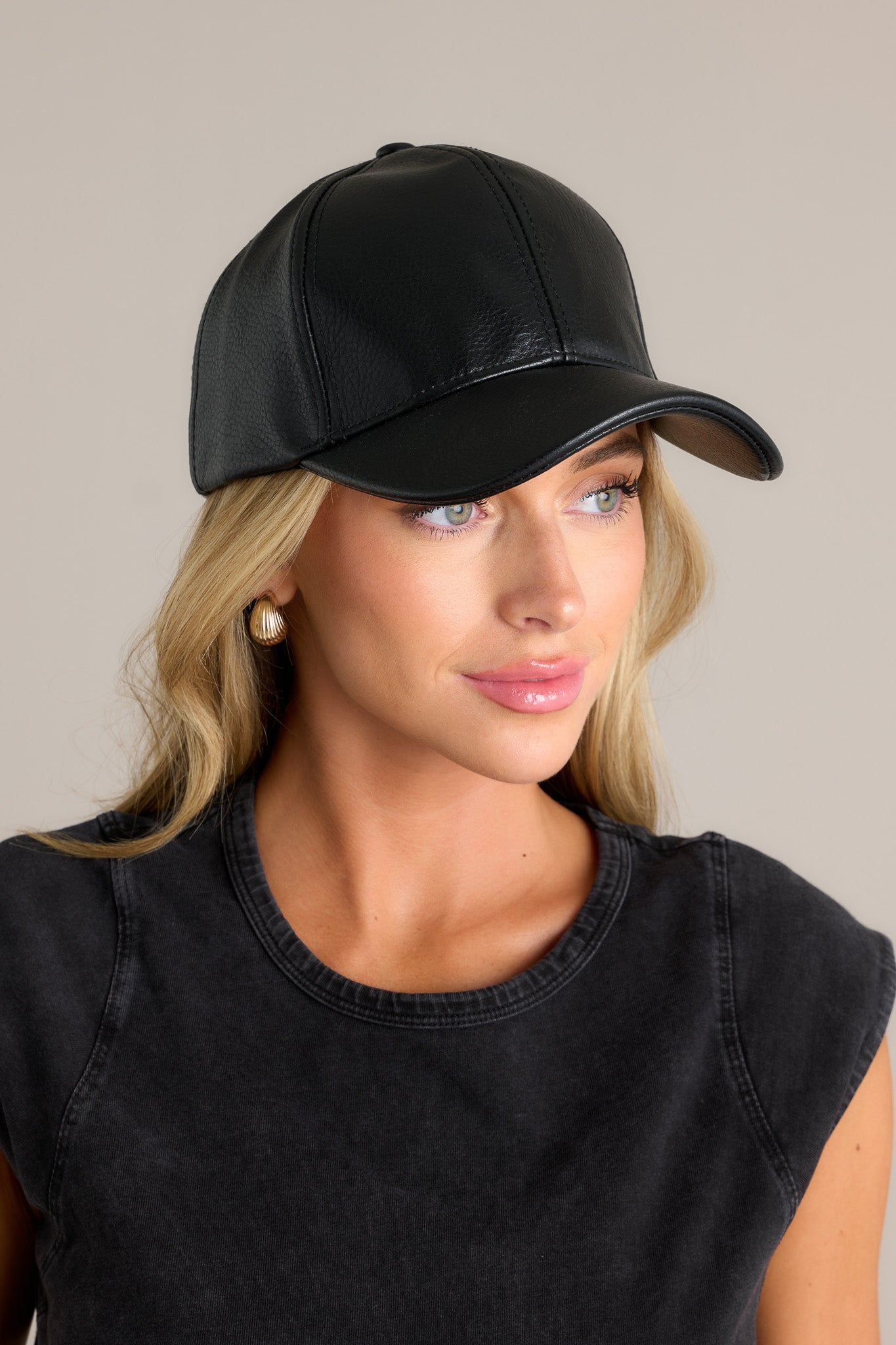 This all black hat features a faux leather material, and an adjustable velcro strap in the back.