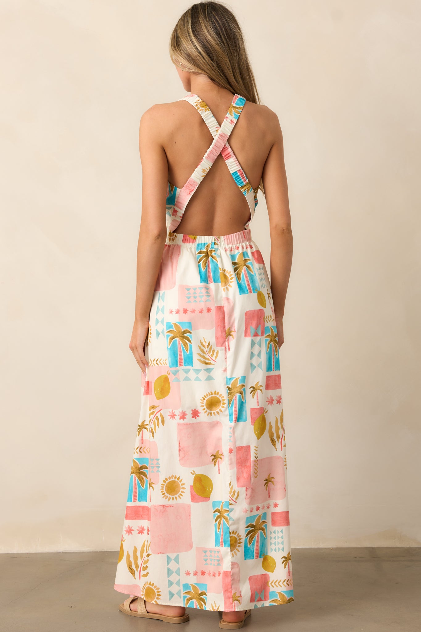 The back of the pink dress, showing the criss-cross shoulder straps and relaxed design with the tropical print flowing down the skirt.