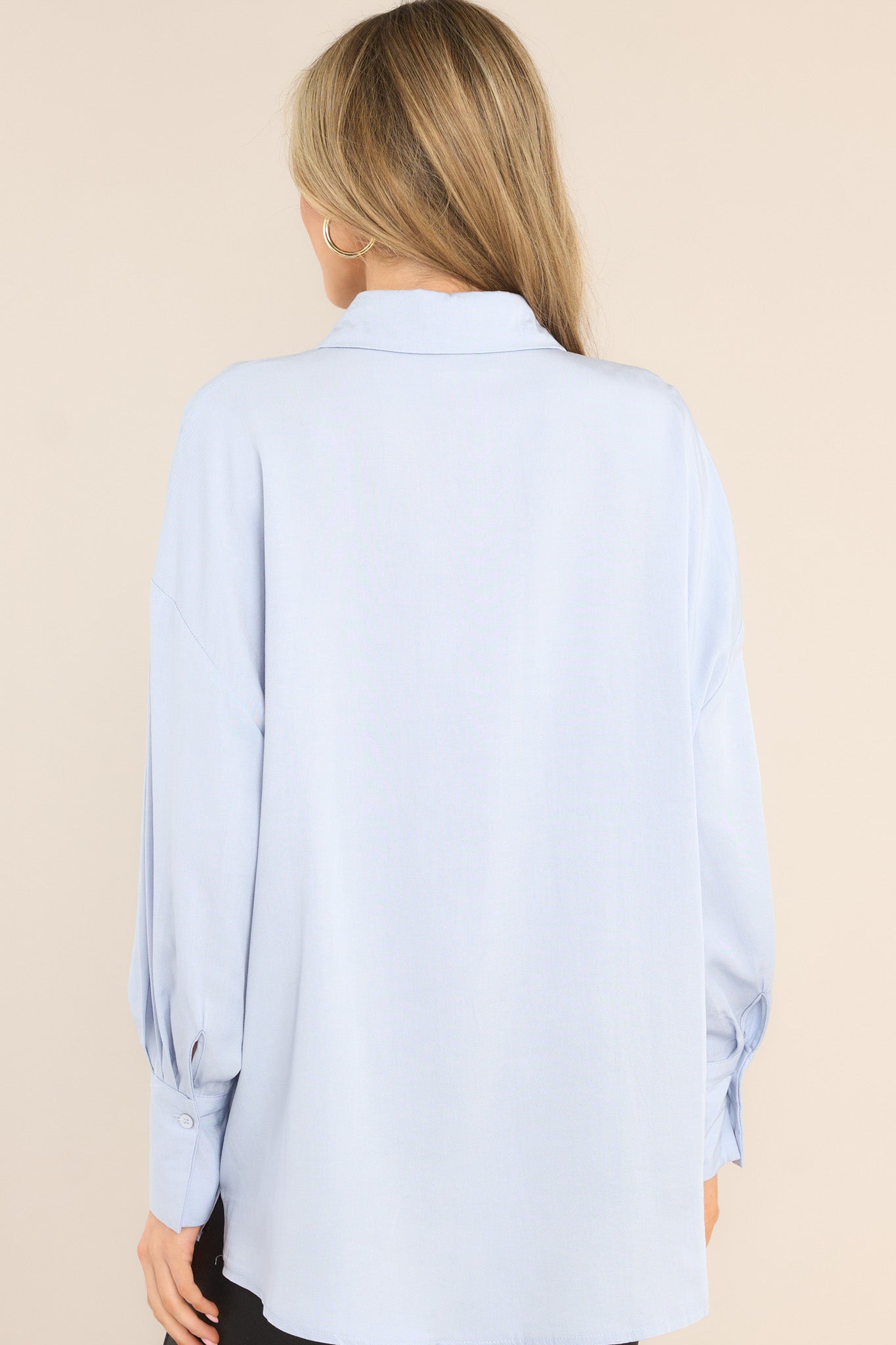 Back view of a light blue top featuring a collared neckline and a dropped shoulder.