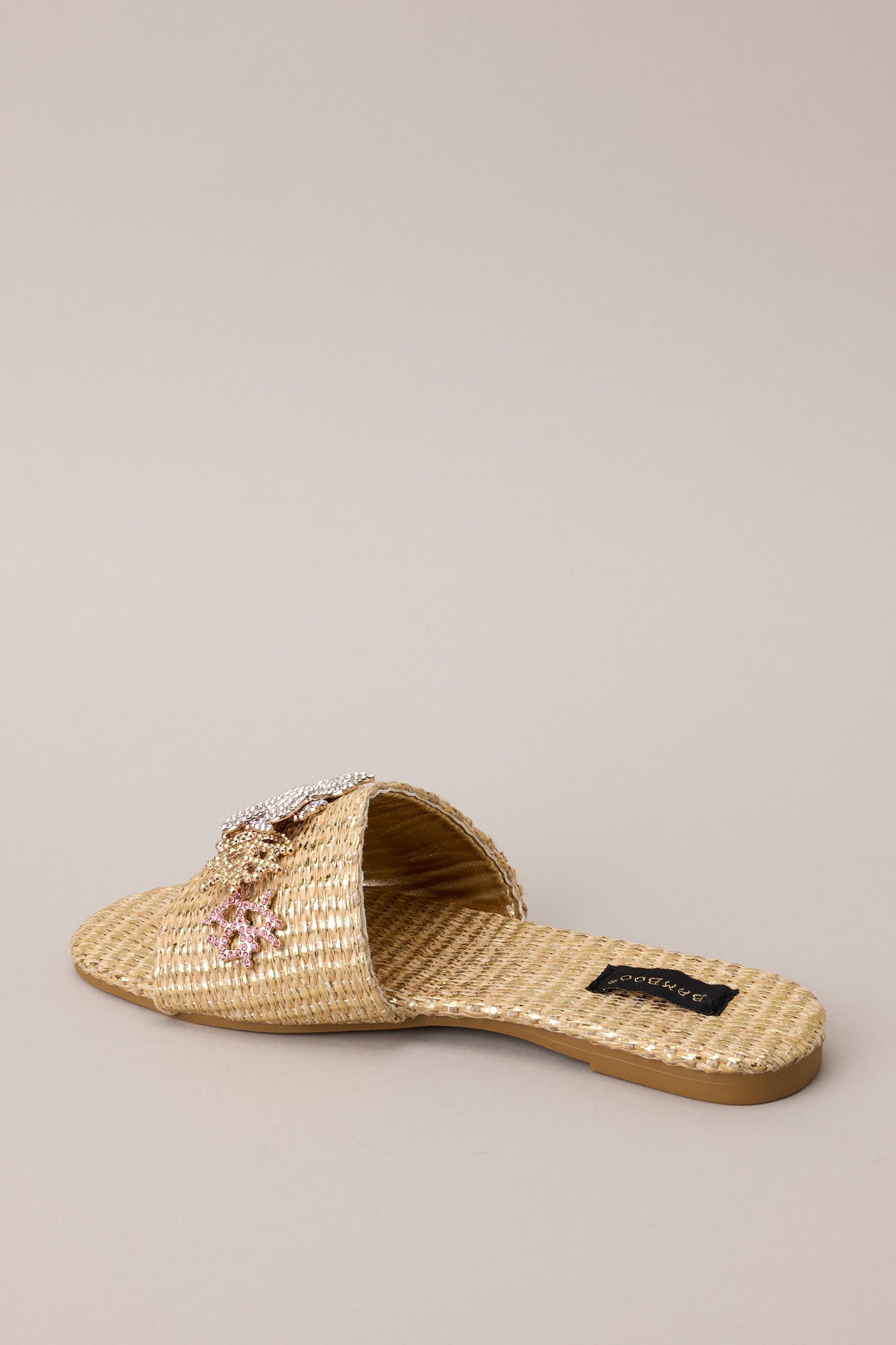 Back view of these sandals that feature a rounded toe, a slip-on design, a wicker-like material, and tropical multicolored rhinestone detailing.