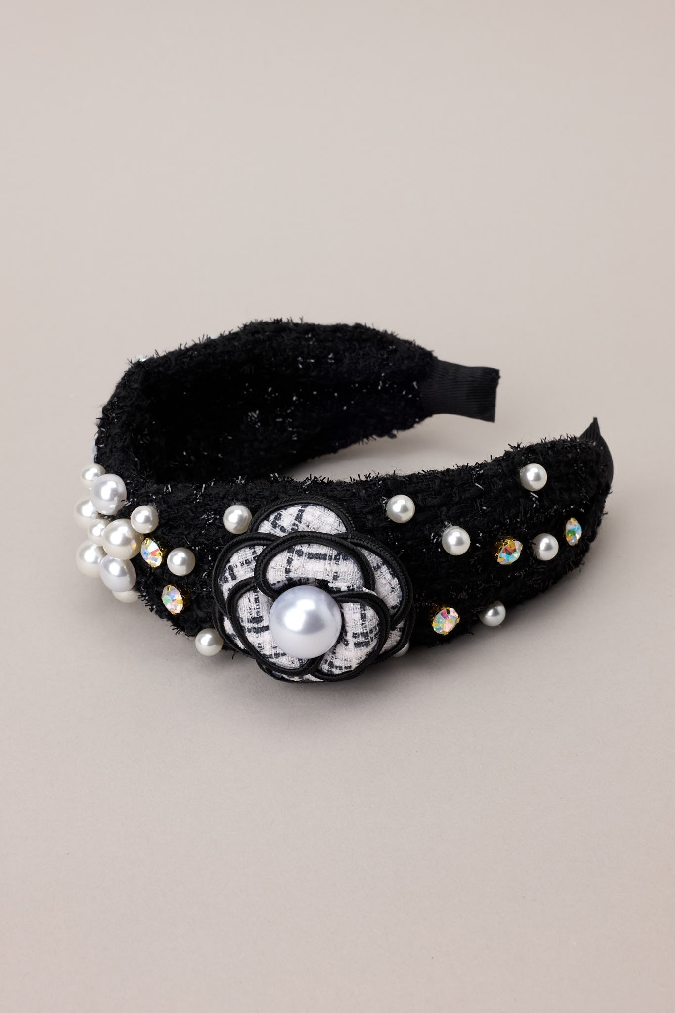 "Black tweed headband adorned with faux pearls and rhinestones, highlighting the textured tweed material.