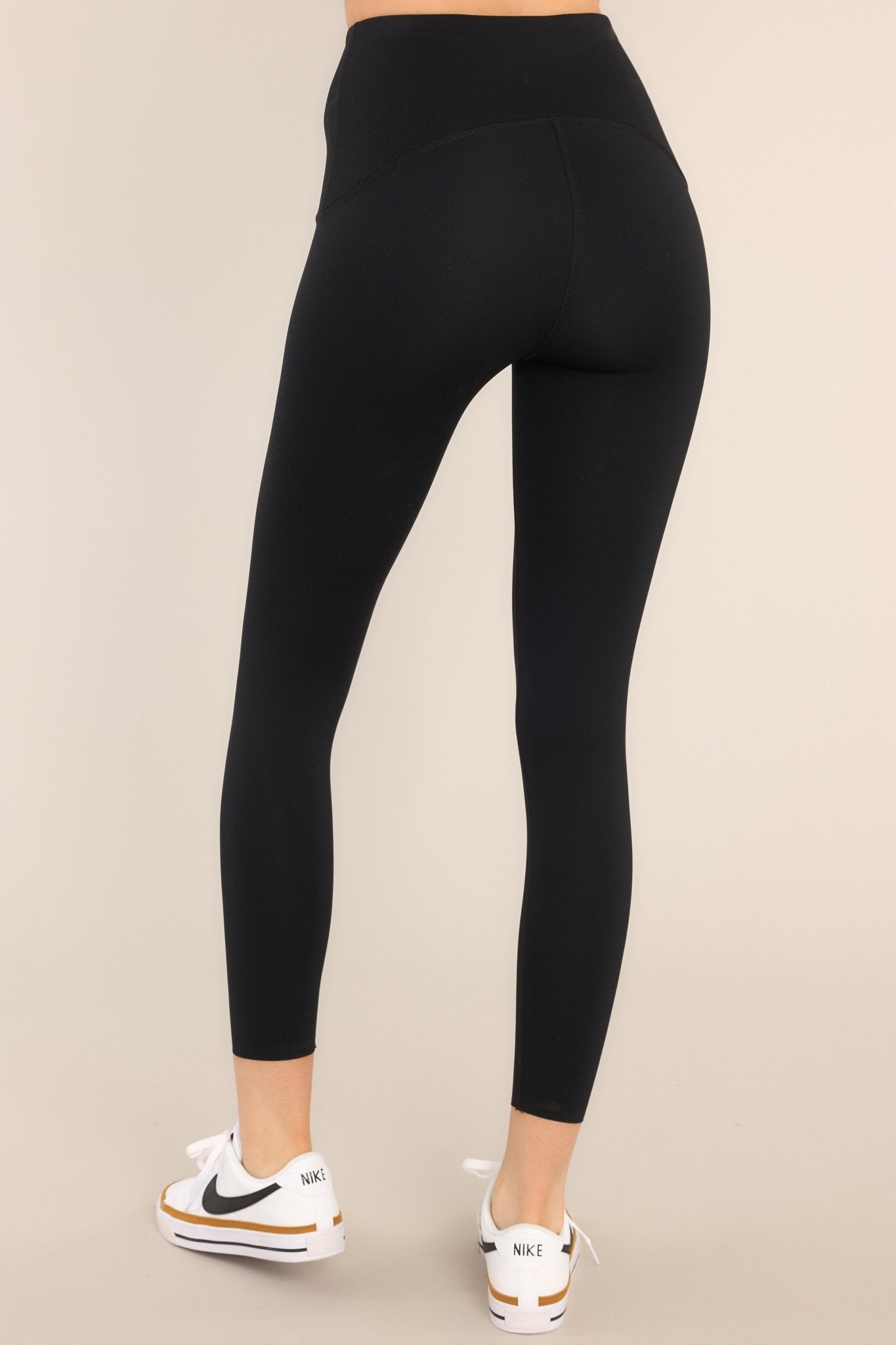 Back view of black leggings featuring a 7/8 length, high-rise contoured waistband, and a hidden pocket.