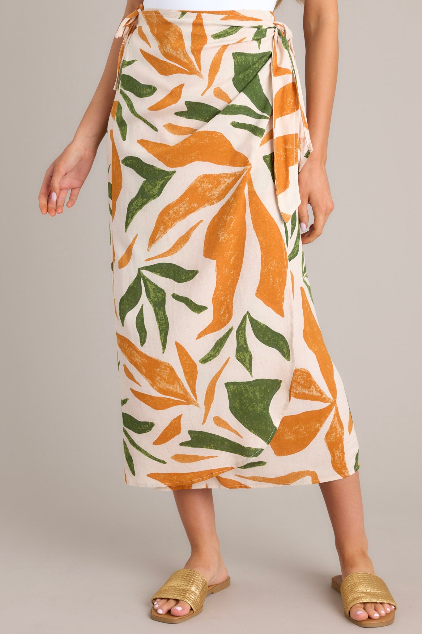 Front view of this tropical print midi skirt that features a high waisted design, an elastic waist insert, self-tie wrap features, an orange & green tropical print, and a lightweight fabric.