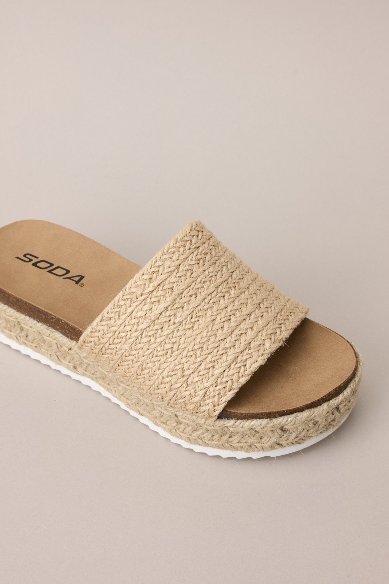 Overhead view of these natural sandals with rounded toe, slip-on design, strap over foot, espadrille detailing, textured sole.