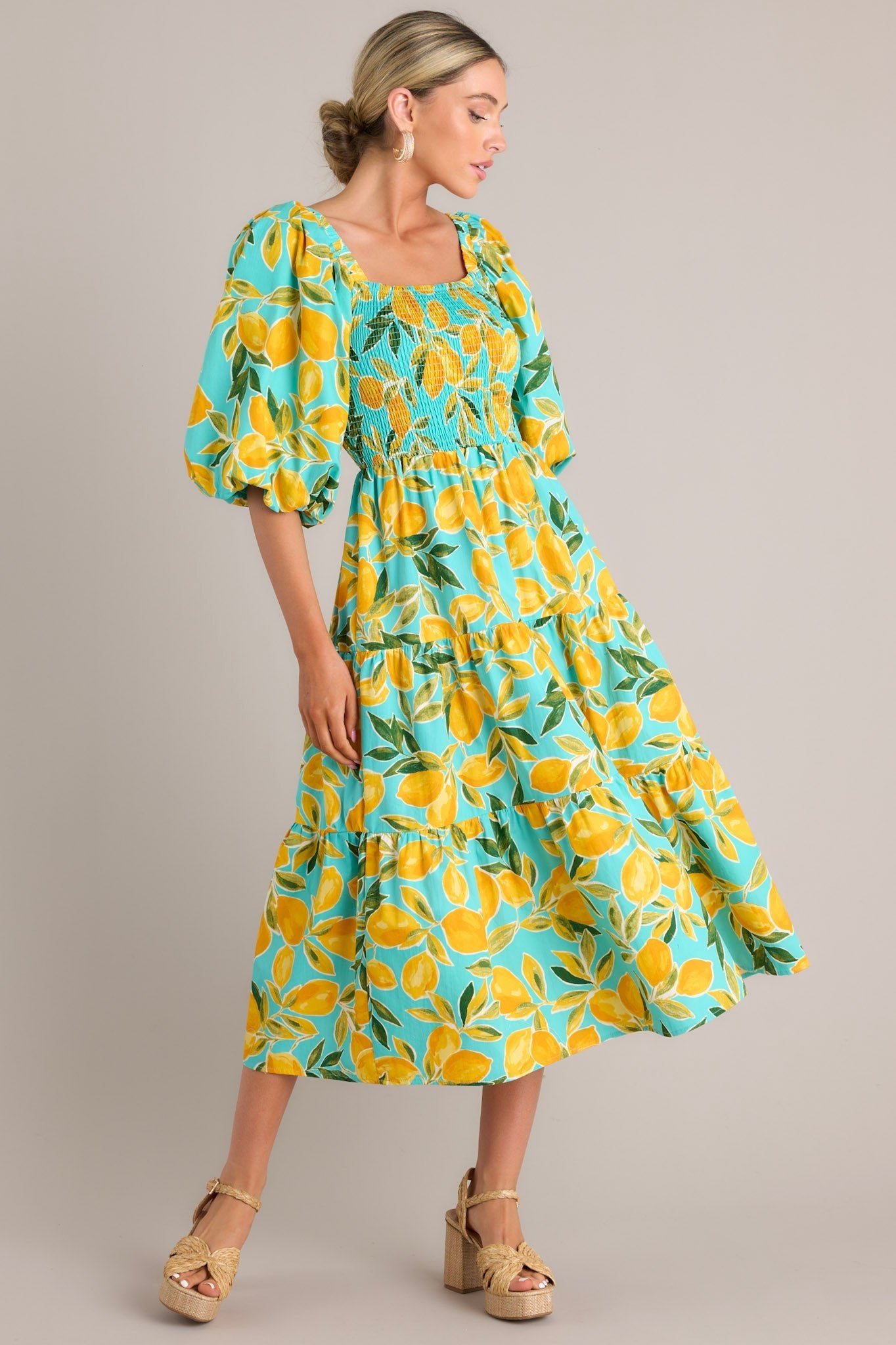 A side profile view of the aqua dress, emphasizing the puff sleeves, smocked details, and colorful lemon print.