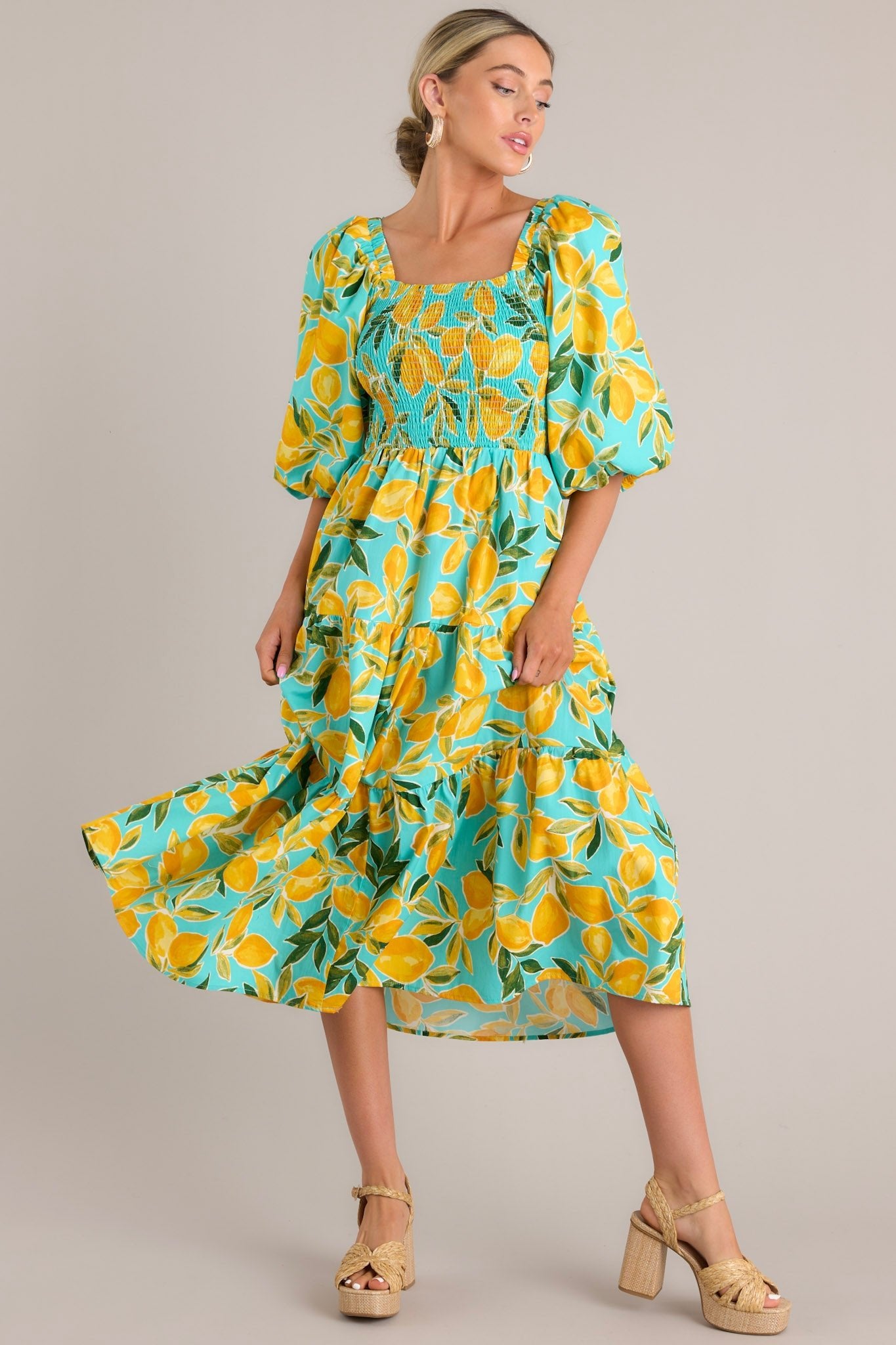 The dress in motion, highlighting the tiered skirt and vibrant lemon pattern against the aqua fabric.