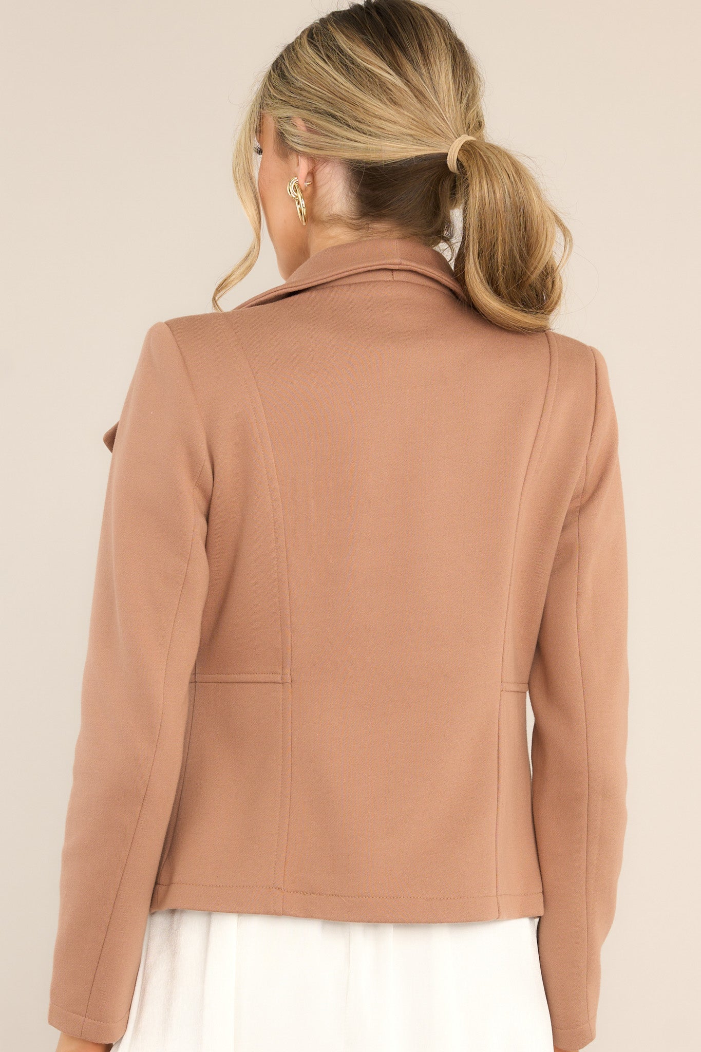 Back view of a mocha tan moto jacket featuring shoulder pads and a streamlined back design with silver hardware details.