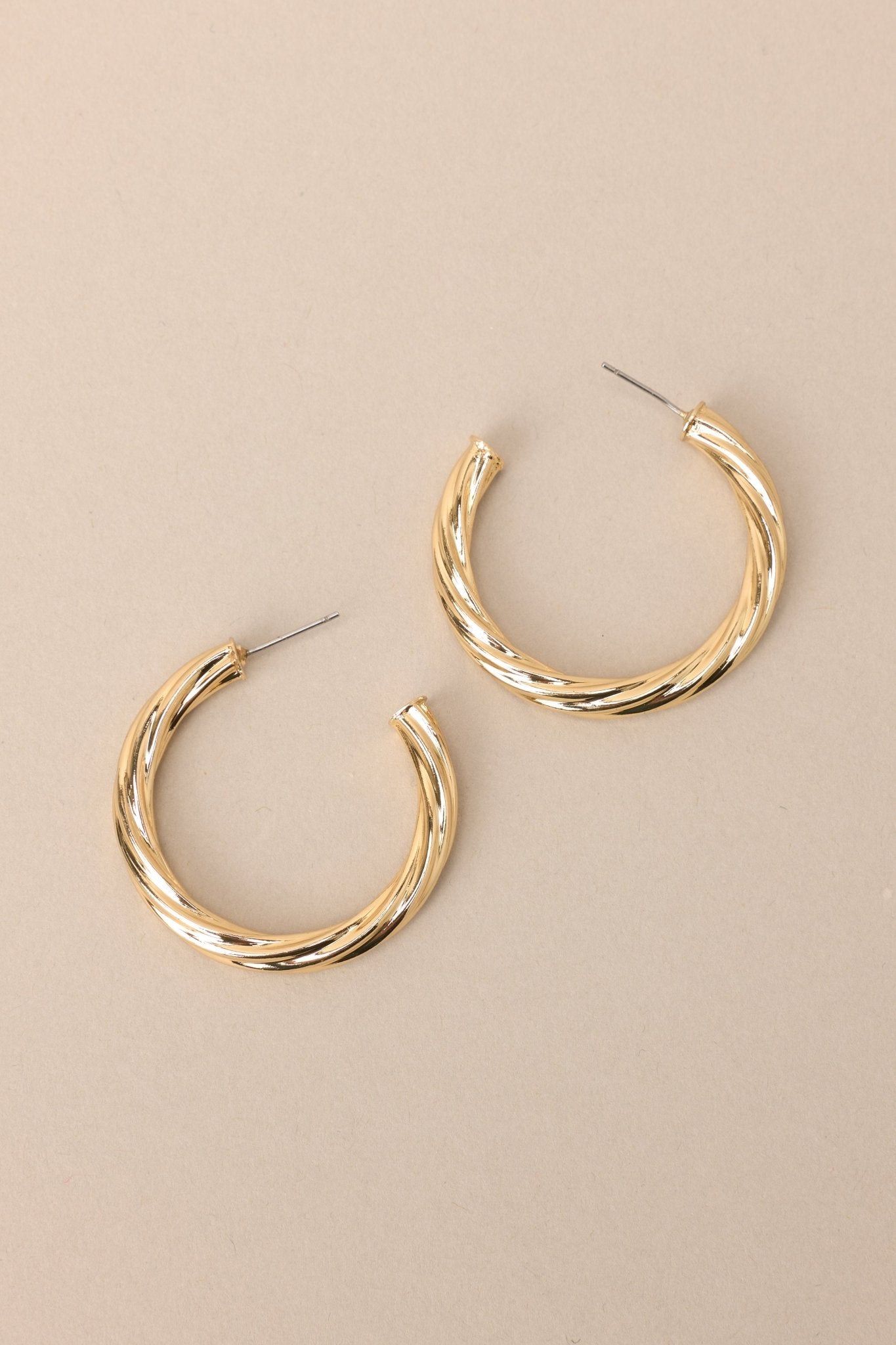 Side view of these earrings feature gold hardware, a twist like design, and a secure post backing.