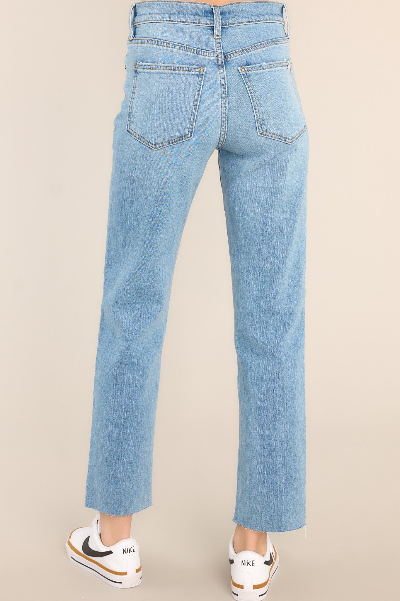 Back view of jeans highlighting the overall fit, pockets, light distressing, and raw hemline.