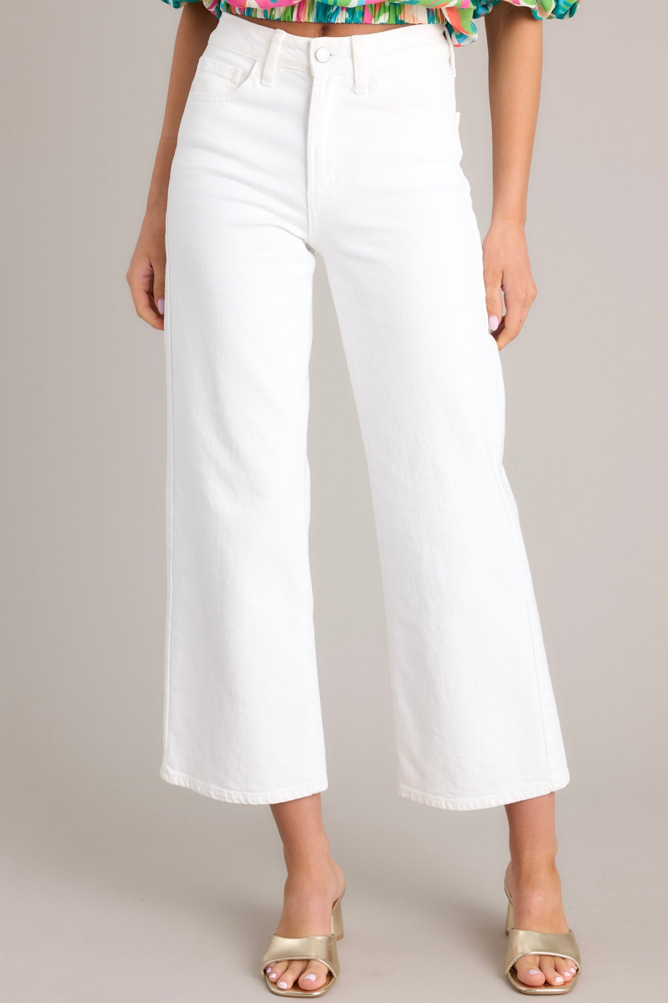 Close up view of these white jeans that feature a high waisted design, classic button & zipper closure, belt loops, functional front & back pockets, and a cropped length.