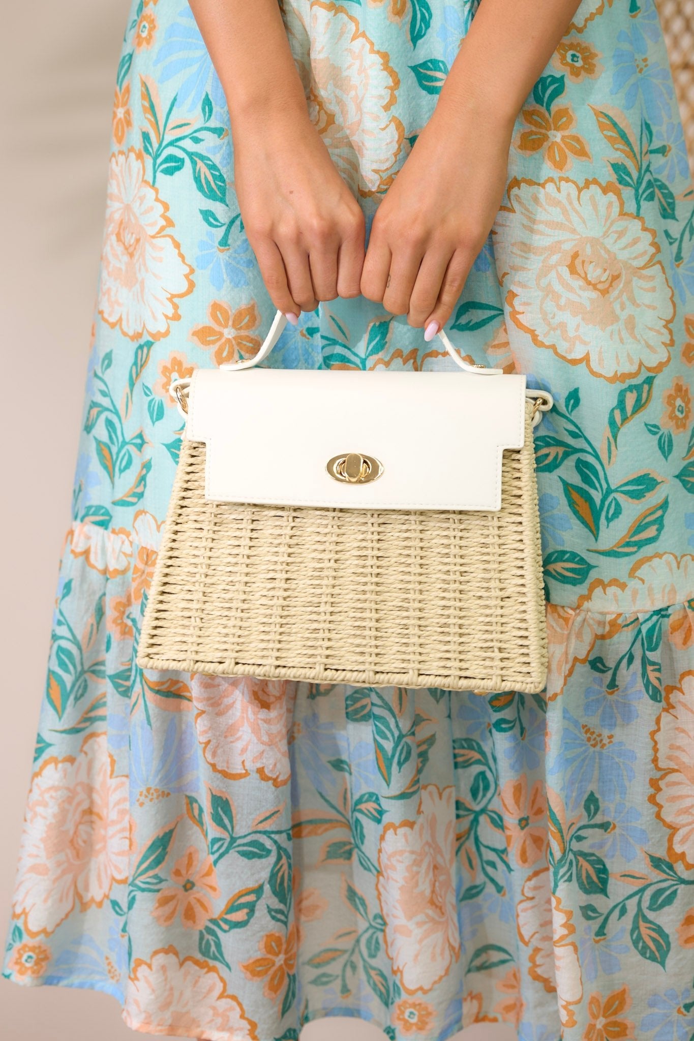 Front view of this woven handbag that features gold hardware, a thick top handle, faux leather, a twist lock closure, a zipper pocket inside and an adjustable shoulder strap.