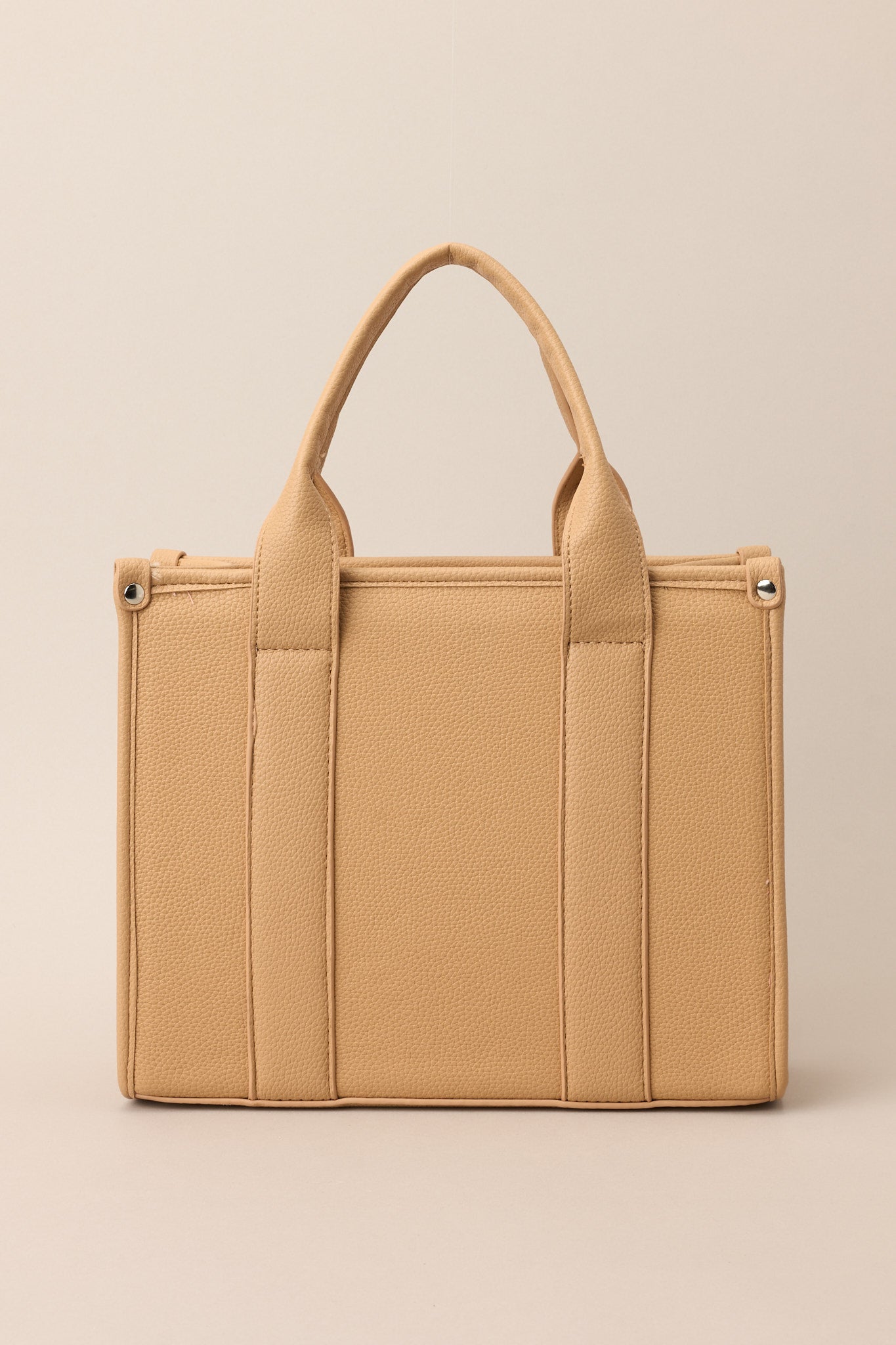 Back view of this tan bag that features silver hardware, top handles, a functional zipper closure, an additional pocket on the inside, and a removable strap.