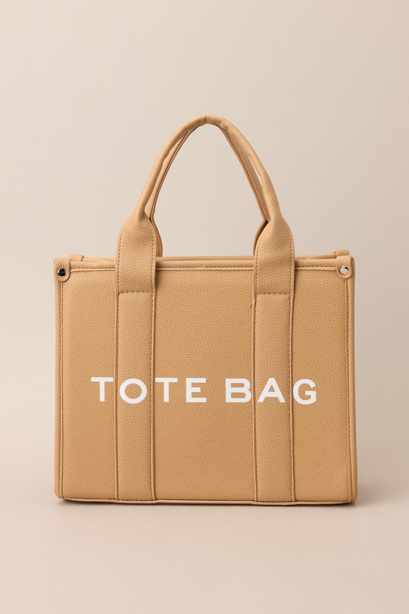 Front view of this tan bag that features silver hardware, top handles, a functional zipper closure, an additional pocket on the inside, and a removable strap.