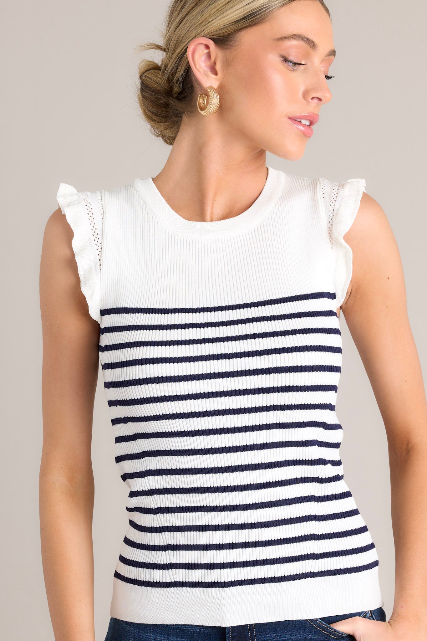 Front angled view of a white & navy striped top featuring a ribbed crew neckline, horizontal stripes, a stretchy knit fabric, and flutter sleeves