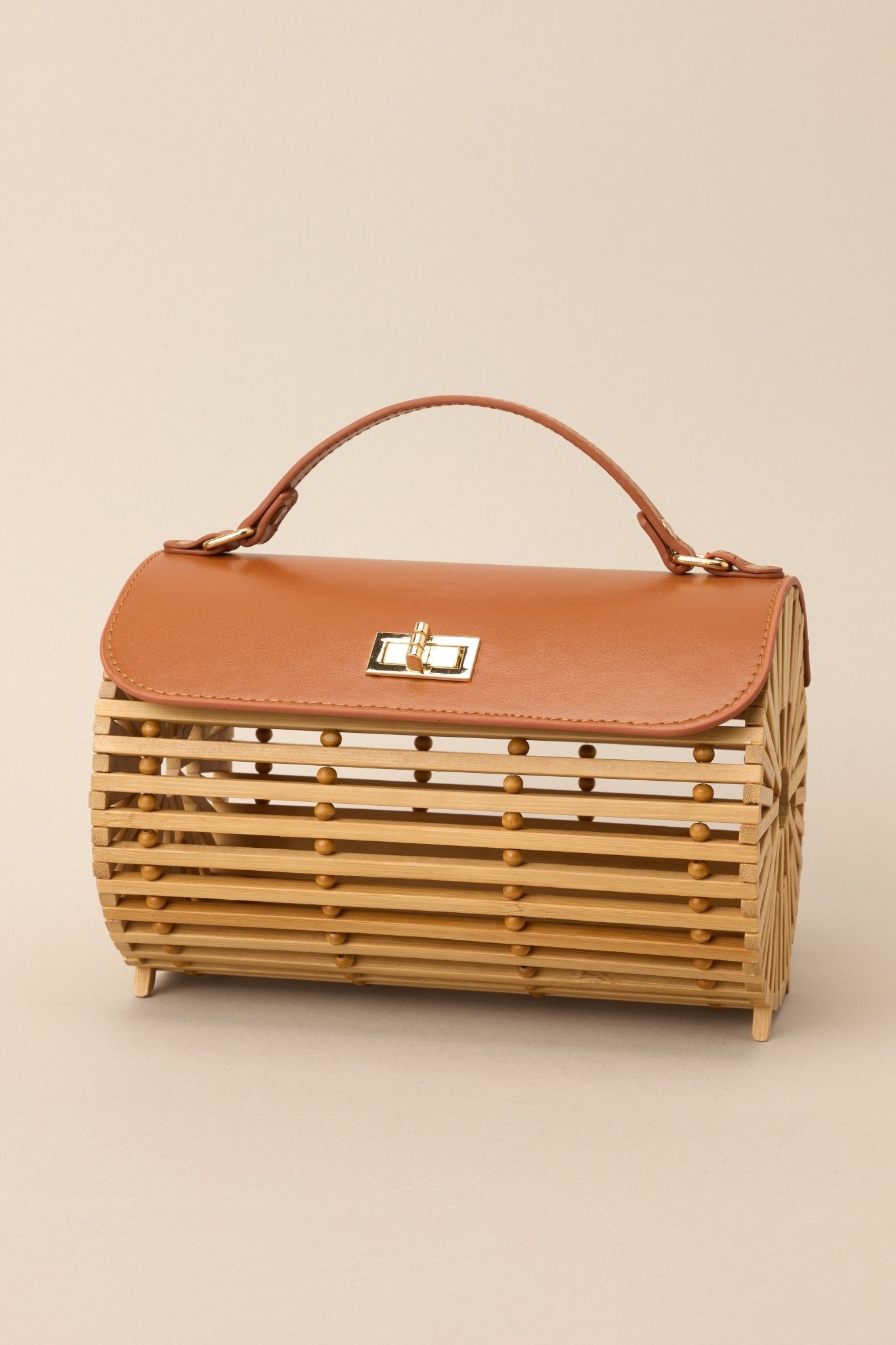 Angled overhead view of this bamboo handbag that features a top handle, a single flap design, a twist lock closure, and a removable chain strap.