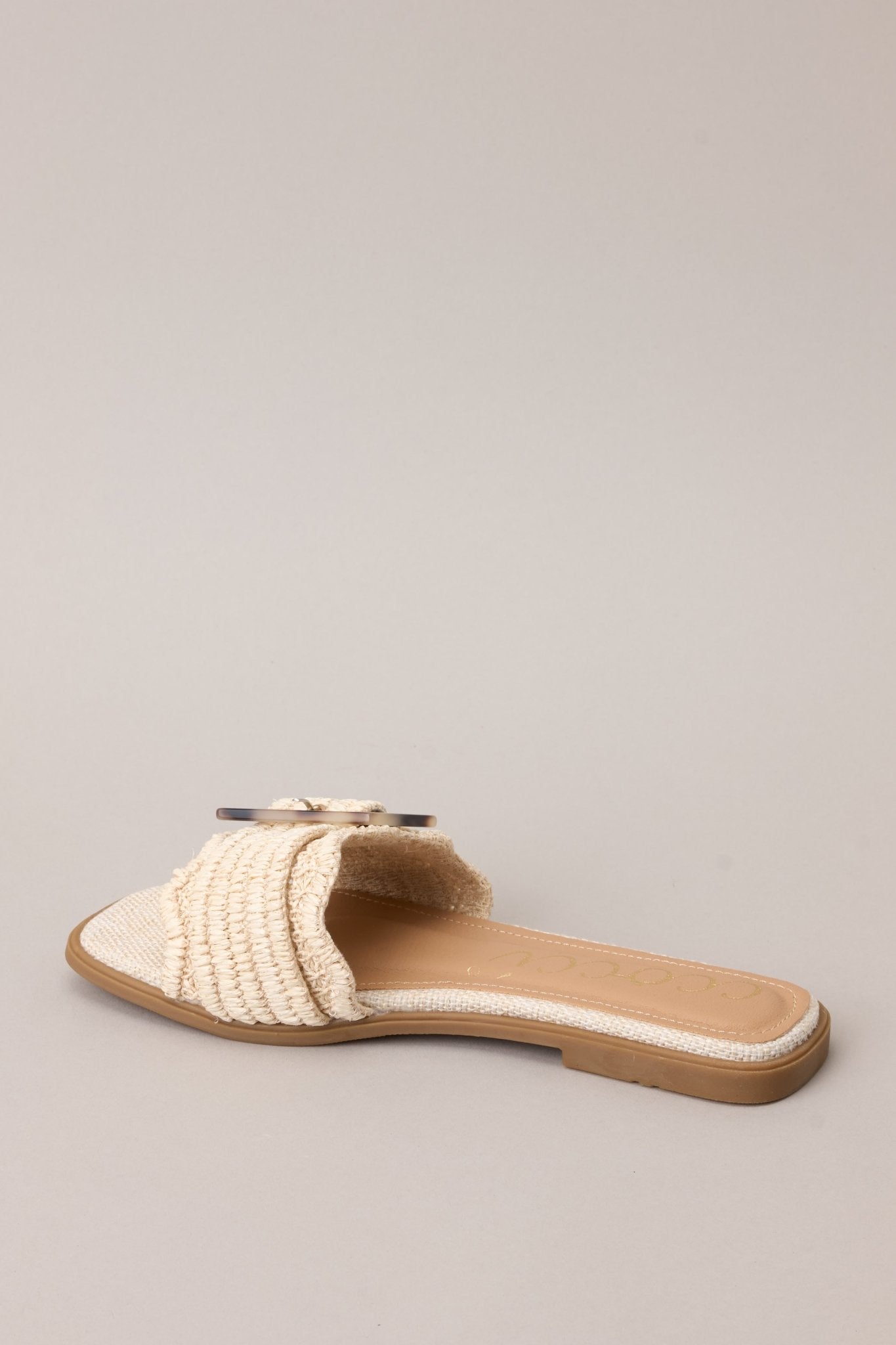 back view of these sandals that feature a square toe, a slip-on design, a strap across the top of the foot, a functional buckle, and a woven textured material.