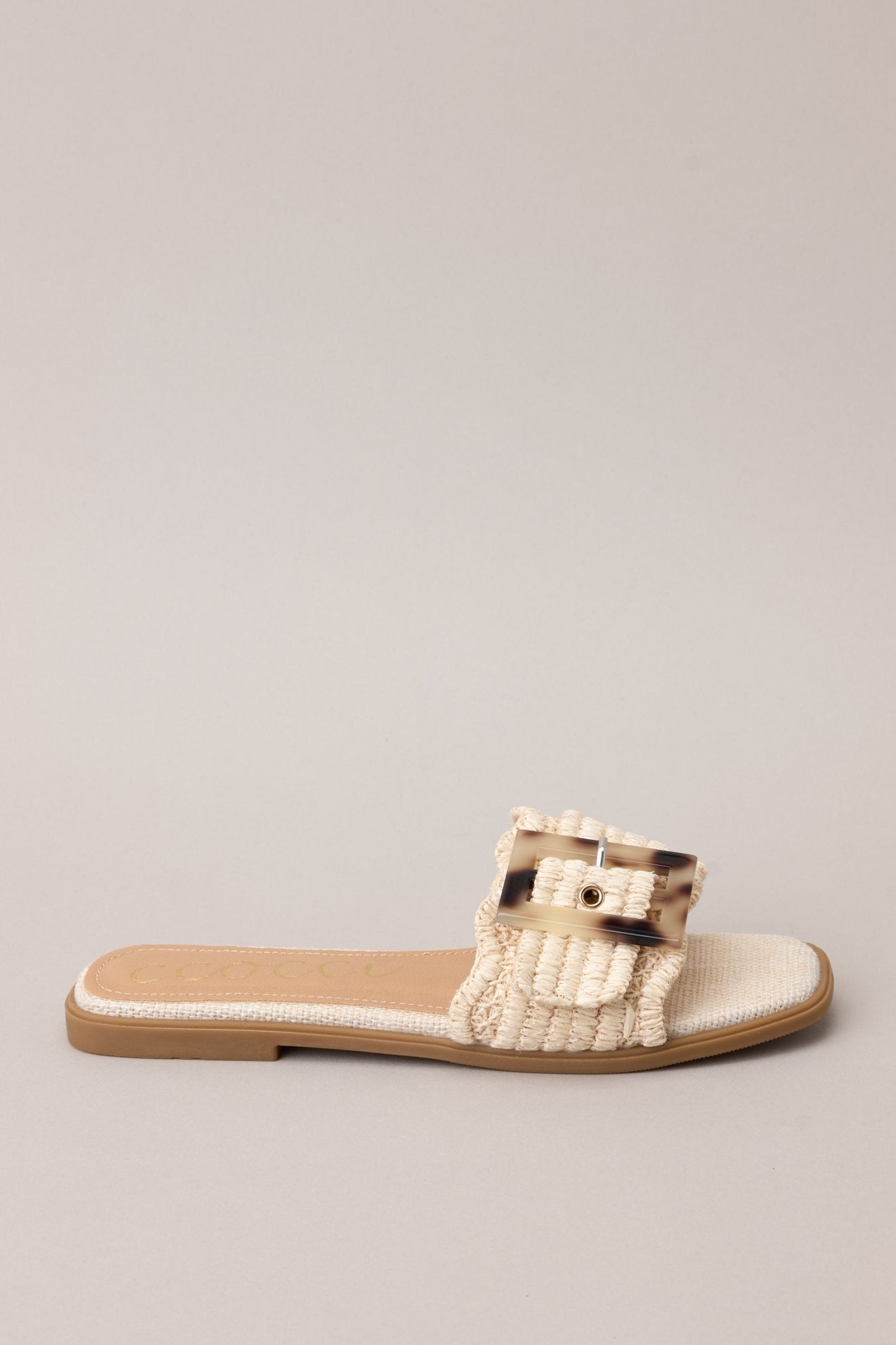 Side view of these sandals that feature a square toe, a slip-on design, a strap across the top of the foot, a functional buckle, and a woven textured material.