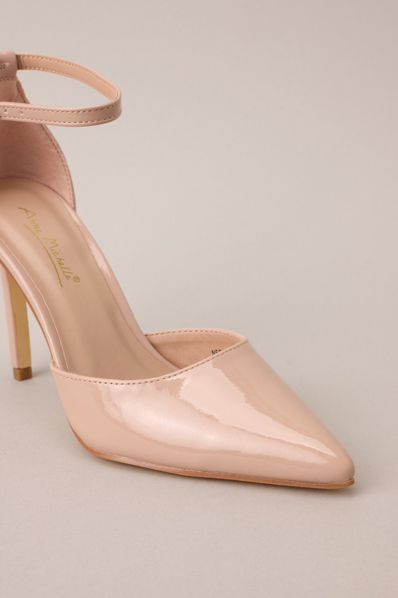 A close-up of the pointed toe, capturing the smooth texture and finish of the beige nude material.