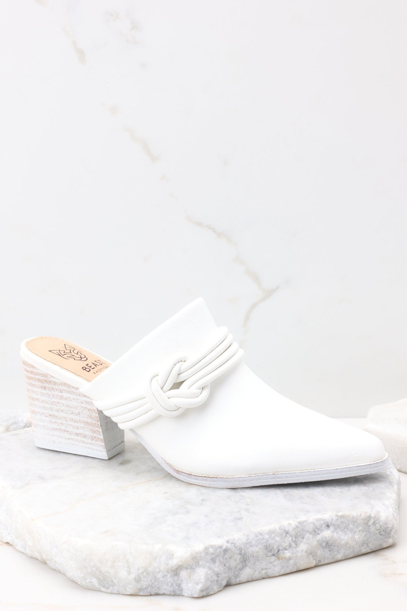 Side view of these shoes that feature a pointed toe, a braided detail across the top of the foot, a slip-on, open back design, and a block heel.