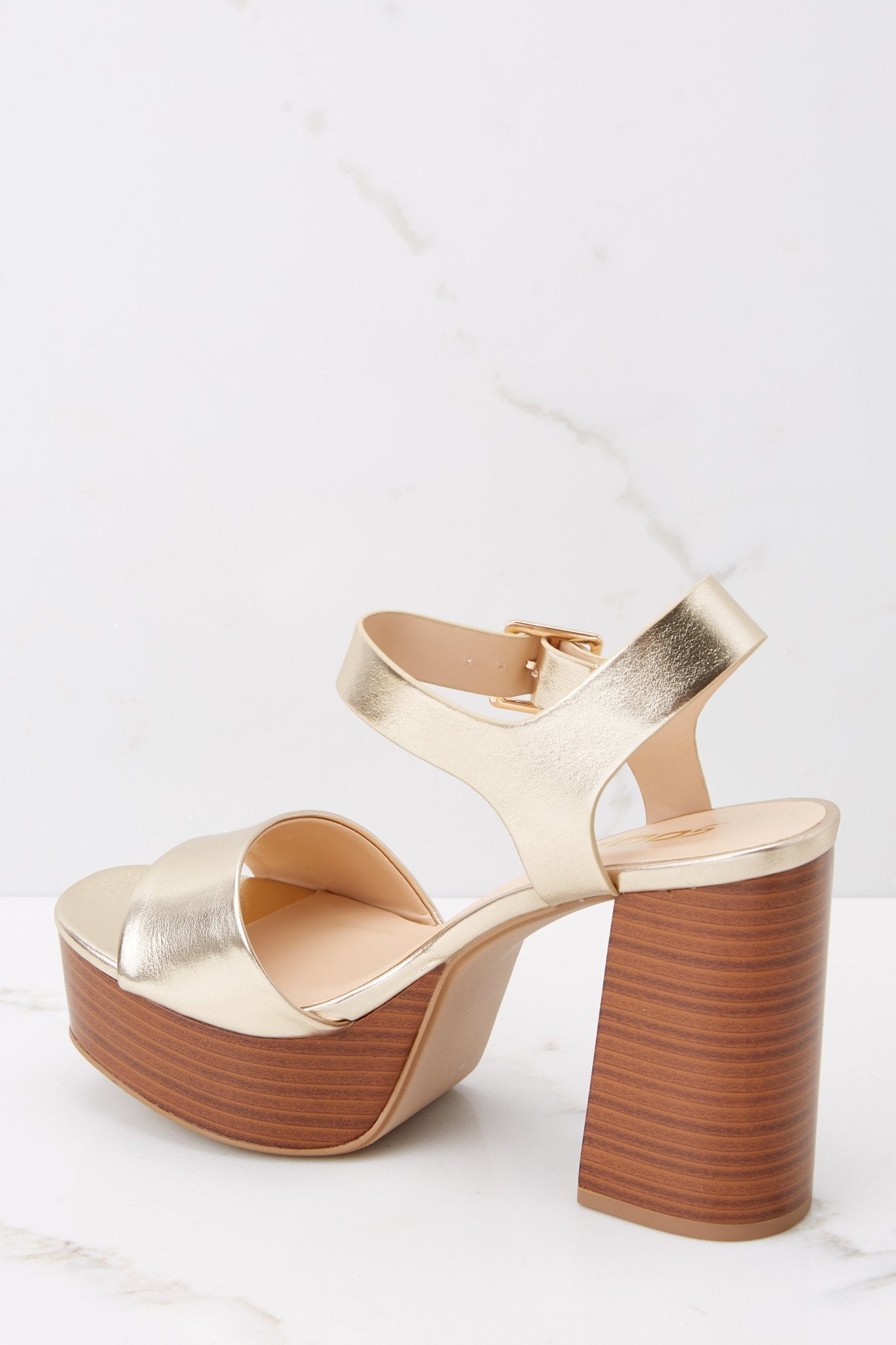 Inner-side view of these shoes that feature an adjustable self-tie around the ankle, thick strap over the toes, and a wooden like platform.