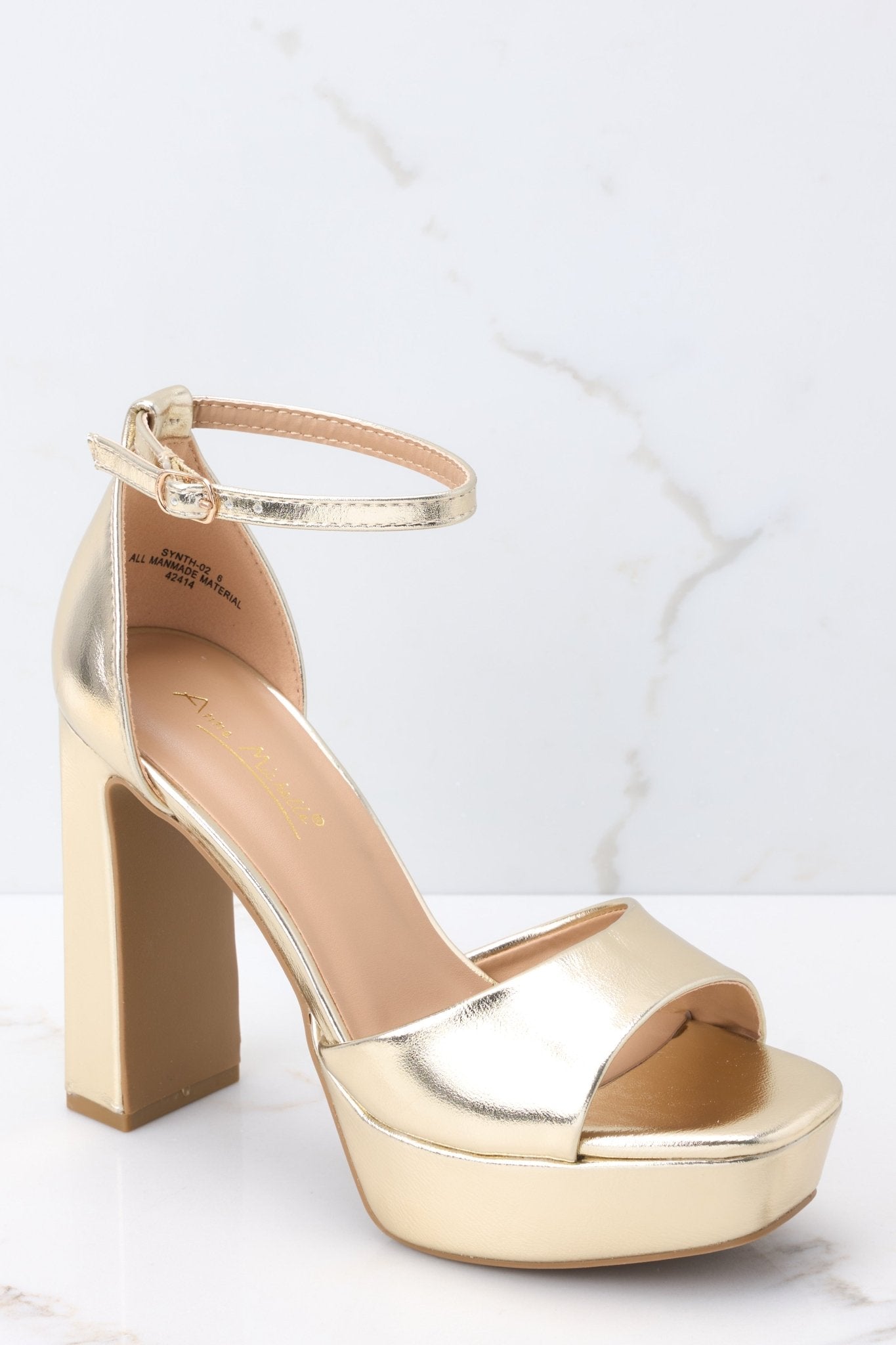 Outer-side view of these shoes that feature an adjustable ankle strap, a gold strap over the foot, a chucky heel, and a platform style. 