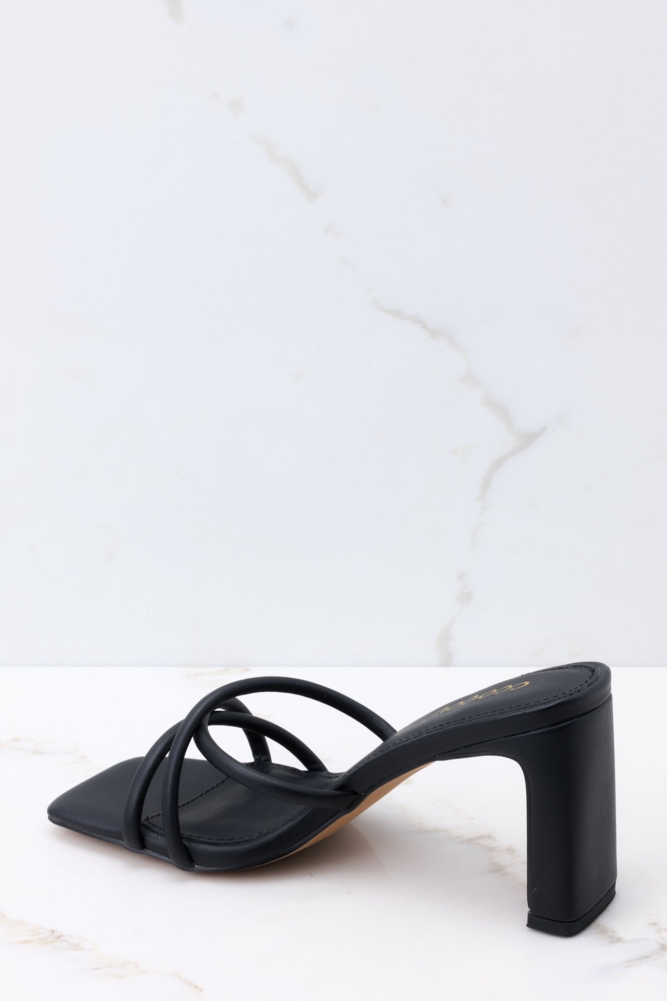 Inner-side view of these sandals that feature a textured black finish, three straps across the top of the foot, a flattened block heel, and light cushioning in the base.